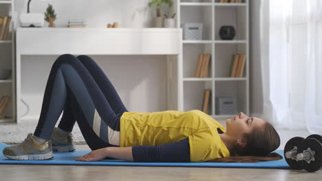 young-woman-is-training-in-apartment-at-weekend-lying-on-floor-and-doing-exercises-for-abdominal-muscles-keeping-fit-and-caring-about-health-good-physical-condition